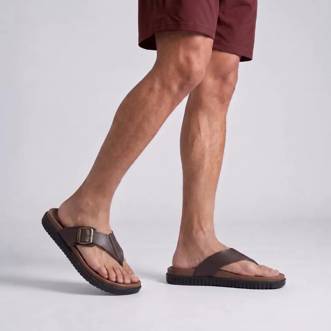 Man walking comfortably in Junction Sole brown buckle slippers, showing lightweight cushioned sole designed for everyday walking comfort in Pakistan.